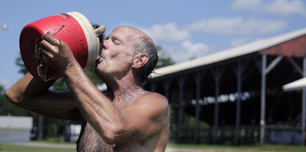 Carnival worker Bill Derick cools off with water Monday while setting up rides at the Pittston Fairgrounds. The 62nd annual agricultural exhibition kicks off Thursday with a dance concert by Motor Booty Affair in the evening and wraps up Sunday with a pig scramble.