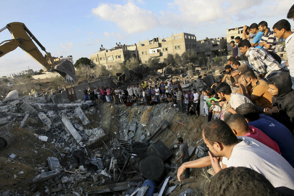 Palestinians gather around the rubble of a building where at least 20 members of the Al Najar extended family were killed by an Israeli strike in Khan Younis, in the southern Gaza Strip, Saturday.