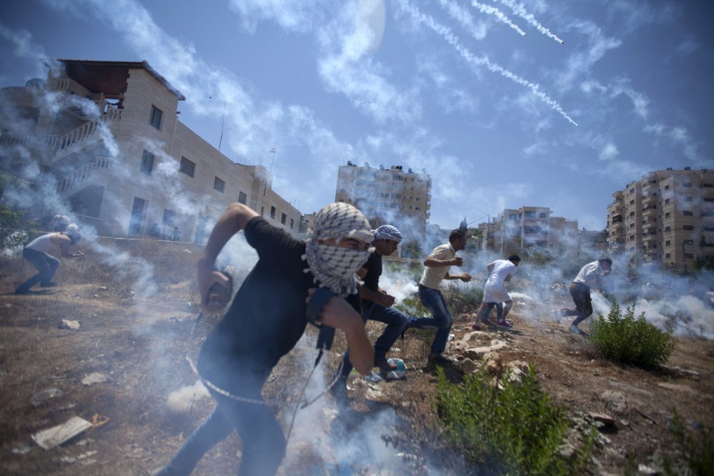 Palestinians run for cover during clashes with Israeli soldiers following a protest against the war in the Gaza Strip, outside Ofer, an Israeli military prison near the West Bank city of Ramallah, on Friday.