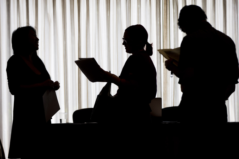 In this June 23 photo, a job recruiter, left, with New Western Acquisitions, meets with employment seekers during a job fair in Philadelphia. As the economic recovery enters its sixth year, many Americans don’t feel better off.