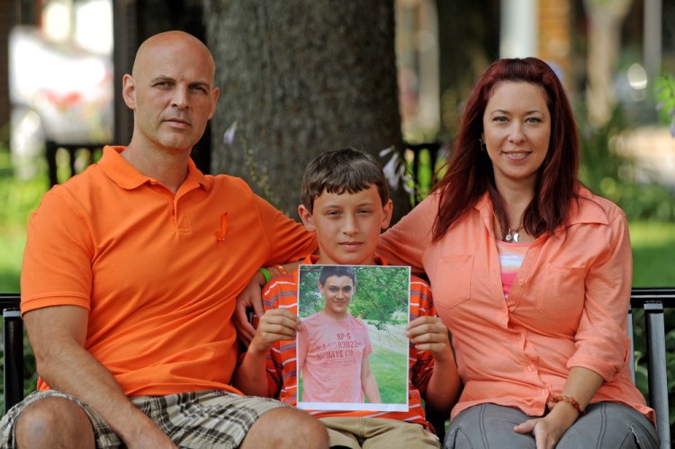 Ray, Nason and Amy Berthelette sit with a picture of Nolan at Castonguay Square in downtown Waterville on Tuesday.