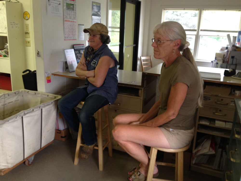 New Sharon residents Georgia Tolman, left, and Mercy Hanson listen to a presentation Tuesday evening on business hours cuts at the town’s post office.