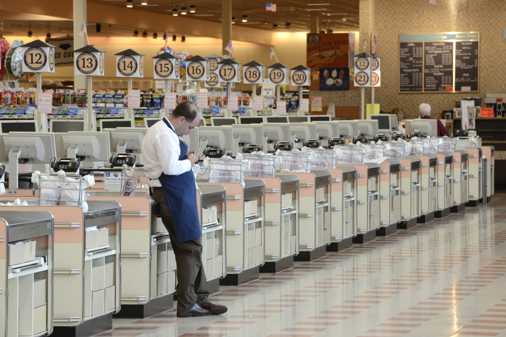 Part-time worker Isaac Ward waits for customers in the checkout area Thursday in Biddeford. A few customers stopped in to buy packaged non-perishable foods, but the store is out of perishable items because most deliveries have stopped.