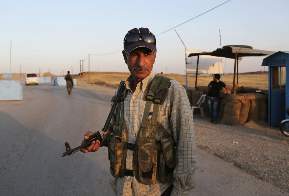 In this Sunday, Syrian Kurdish Peshmerga fighters stand guard at a camp in Derike, Syria.