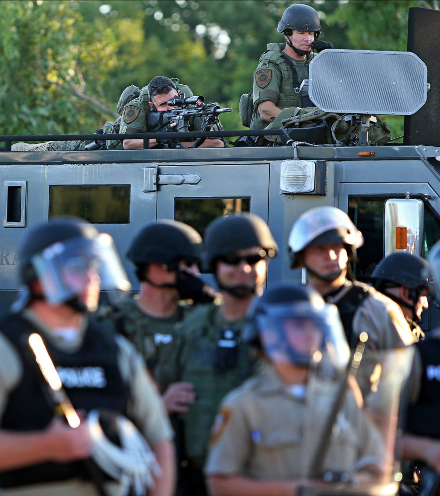 A police sharp shooter keeps an eye on protesters along W. Florissant Avenue on Tuesday, near the QuikTrip that was burned down a few days earlier in Ferguson.