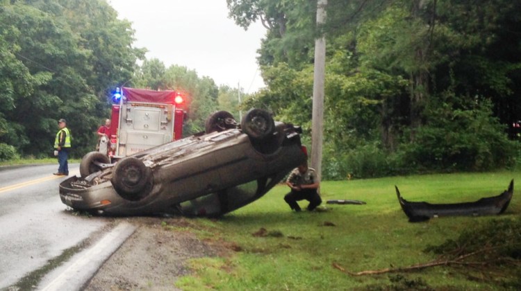 Kennebec County Sheriff’s Deputy Brittany Morin examines a car that flipped over on West River Road in Sidney on Wednesday afternoon. Morin said speed and weather appeared to be factors in the crash.