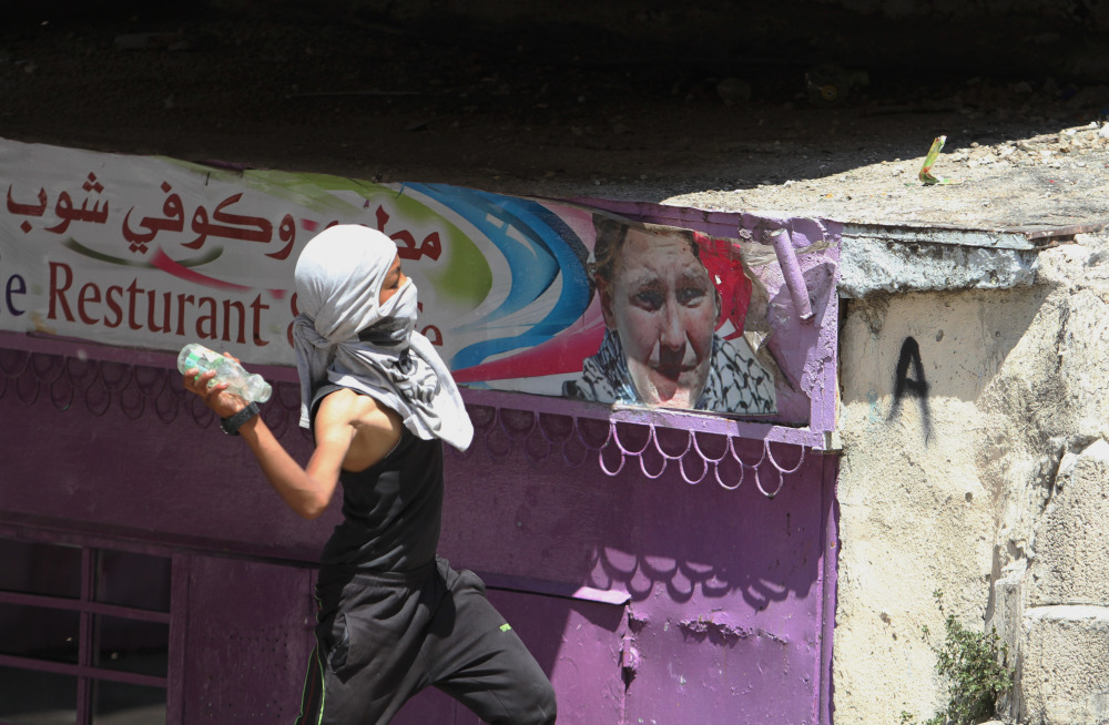 A Palestinian protester throws a glass bottle at Israeli soldiers during clashes, following a protest against the Israeli military action over Hamas in Gaza, in the West Bank city of Hebron on Friday.