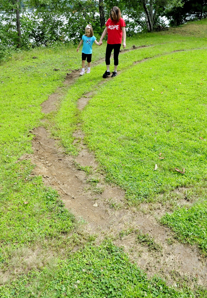 Staff Photo by David Leaming
Margaret Rodrique and her daughter Emma walk on the vehicle tracks that damaged the lawn at a park across from the China Baptist Church on Sunday. Parishioners discovered the vandalism when they arrived for services Sunday. “I am mad and sad,” Emma said.