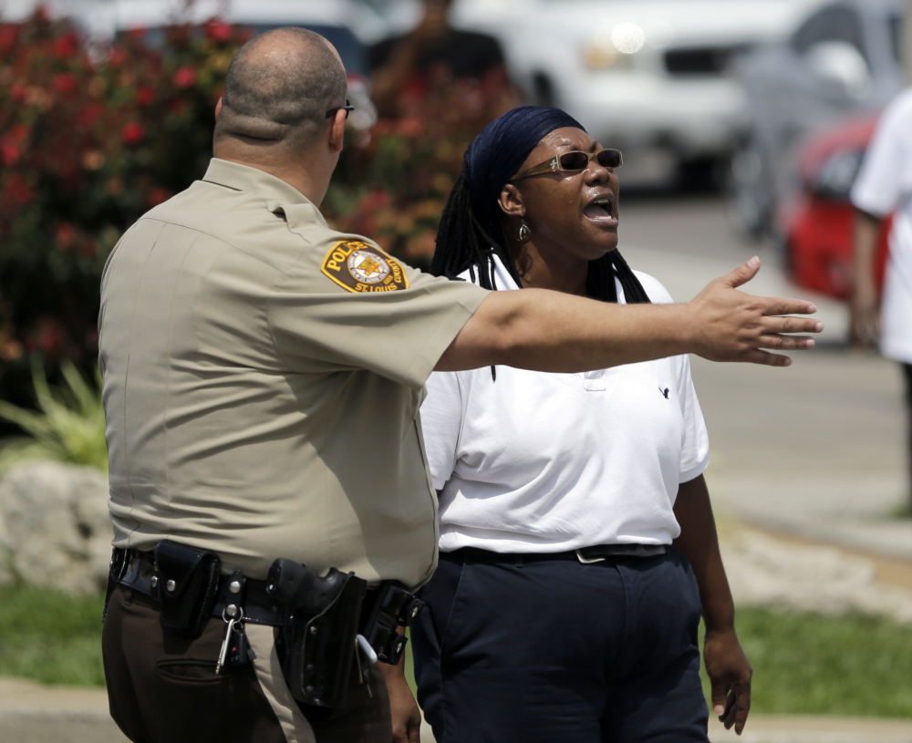 A St. Louis County Police officer tells a woman to keep moving on Monday during protests that were more peaceful than those in Ferguson, Missouri, on Sunday. Gov. Jay Nixon lifted a midnight-to-5 a.m. curfew.