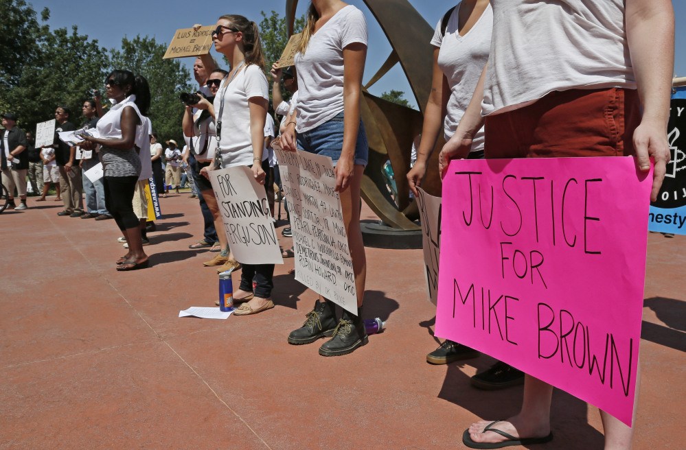 Participants hold signs at a rally in Oklahoma City on Thursday in response to the shooting death of 18-year-old Michael Brown in Ferguson, Mo.