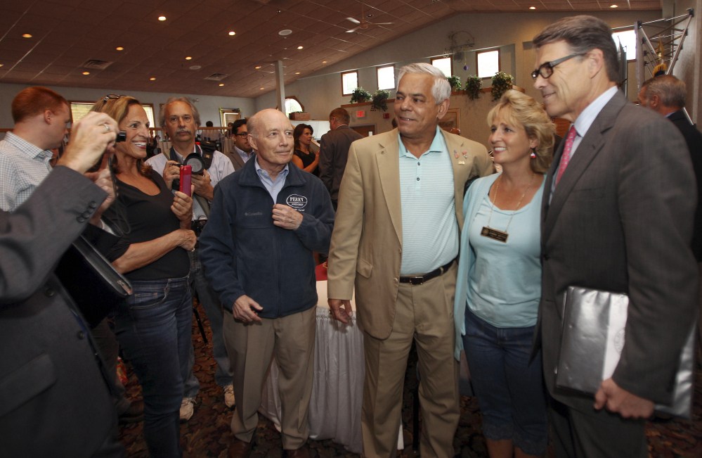 Texas Gov. Rick Perry, right, poses for photos during an Americans for Prosperity dinner event on Friday in Manchester, N.H.