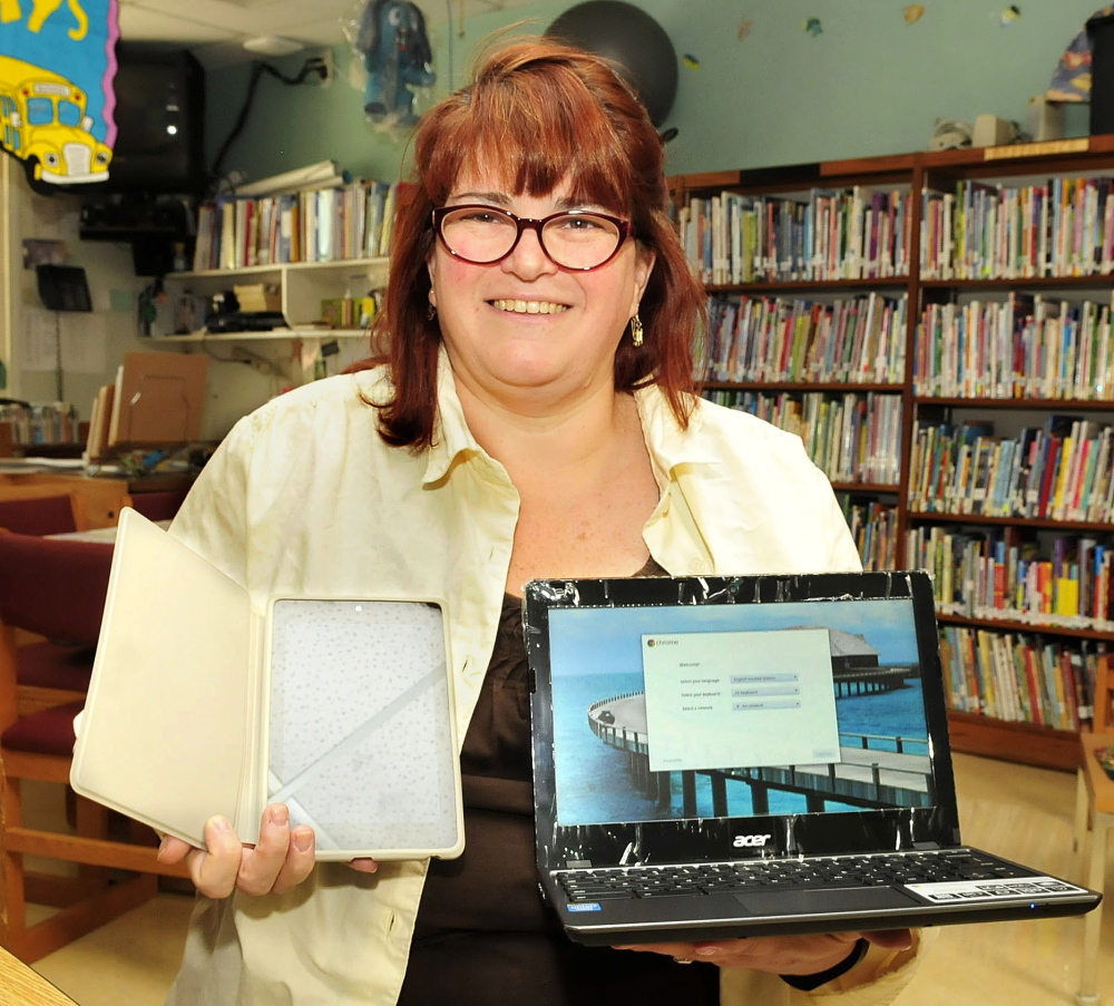 Athens Community School Principal Cindy Streznewski holds some of the new tablets and laptops that will be available to students this school year.