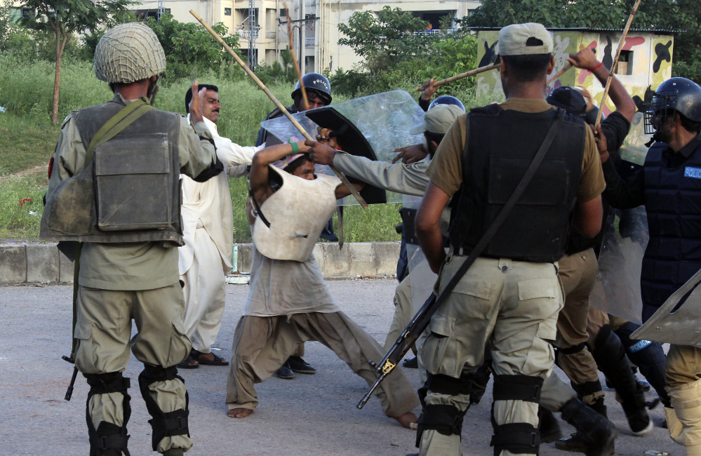 Police beat a protester during clashes in Islamabad, Pakistan on Monday. The violence comes as part of the mass demonstrations led by Muslim cleric Tahir-ul-Qadri and opposition politician Imran Khan that demand Prime Minister Nawaz Sharif resign.