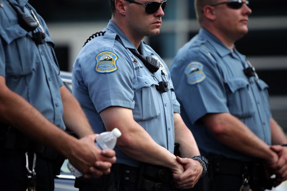 Police officers wear what appear to be body cameras as they hold the line against protesters gathered at the police station during a rally in Ferguson, Mo. on Saturday for Michael Brown, an unarmed black 18-year-old who was fatally shot by a white police officer three weeks earlier.