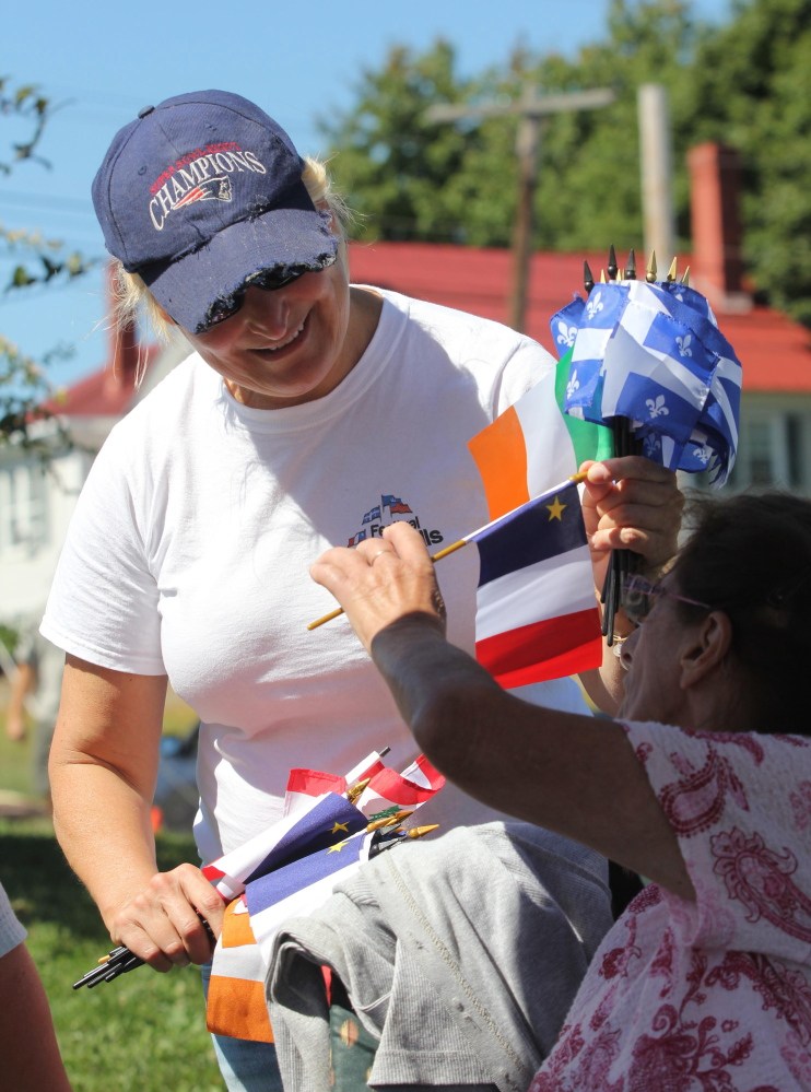 Karen Rancourt-Thomas, coordinator of the Festival at the Falls, passes out Irish, Acadian, Quebec, Scottish and Lebanese flags on Sunday. The festival, formerly known as the Franco-American Family Festival, was reinvented this year to celebrate a wider variety of Waterville’s cultural heritage.
