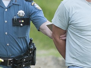 Maine State Police Trooper Scott Duff leads Marc Alberi of Newport to his cruiser in handcuffs after serving him with a search warrant on Monday.