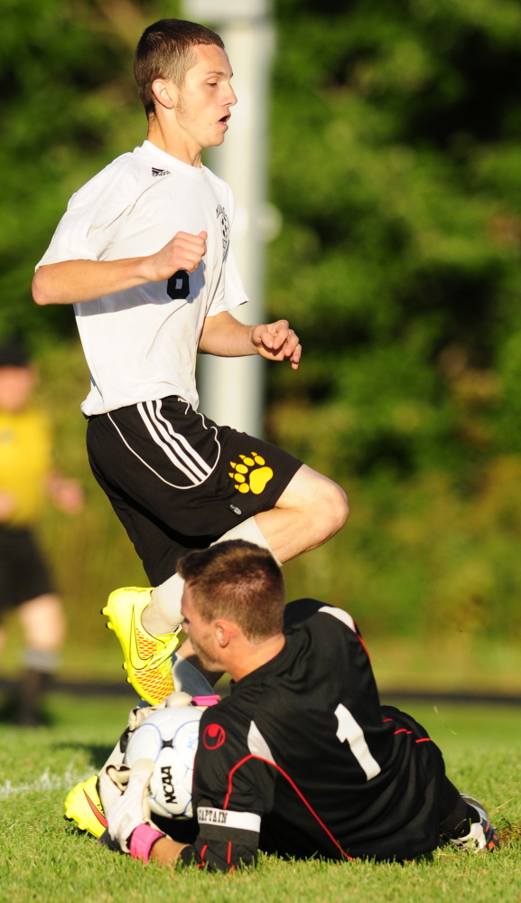 Maranacook striker Kodey Solmitz jumps over Winslow keeper Alex Bedard after he blocked the shot Tuesday at the Ricky Gibson Field of Dreams in Readfield.