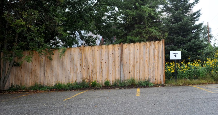 A newly erected 9-foot-high fence separates the New Balance factory from the Ames residence on Depot Road in Norridgewock.