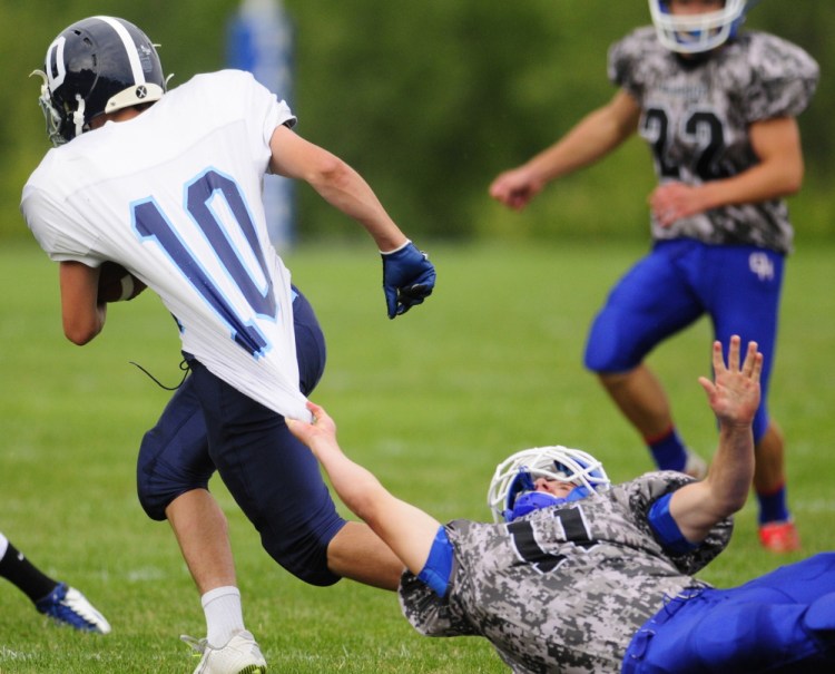 Dirigo halfback Joe Casey gets snagged by Oak Hill defensive back Jonah Martin Saturday at Oak Hill High School in Wales. The Cougars beat the Raiders 14-6, snapping an eight-game winning streak for Oak Hill, the longest active streak in the state.