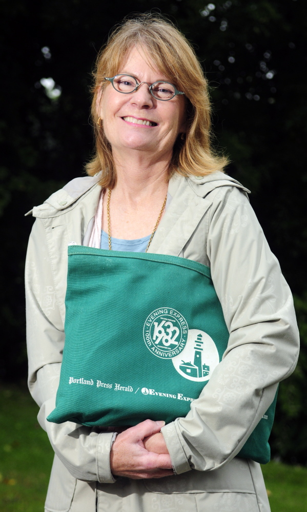 Genie Gannett poses with a bag from the Press Herald and Evening Express on Thursday in Augusta. Her family once owned those papers along with the Kennebec Journal and Morning Sentinel.