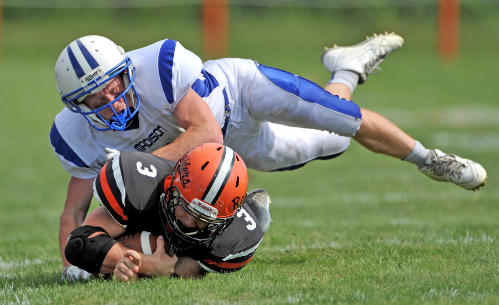 Winslow High School’s Dylan Hapworth (3) is tackled by Madison High School’s Cody Soucier (3) in Winslow on Saturday, Sept. 6.