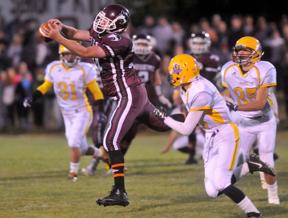 Maine Central Academy’s Mitchell Hallee (34) hauls in a pass as Bucksport’s Hayden Craig, right, tries to defend during a game Friday night.