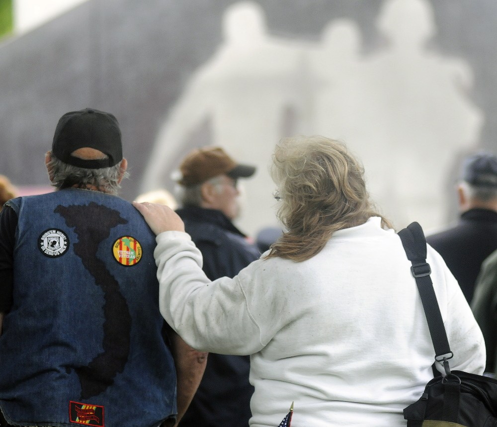 Donna Arsenault of Livermore Falls rests her hand Sunday on the shoulder of her husband, Vietnam veteran Joseph Arsenault, during a remembrance for military service during the Vietnam era at Capitol Park.