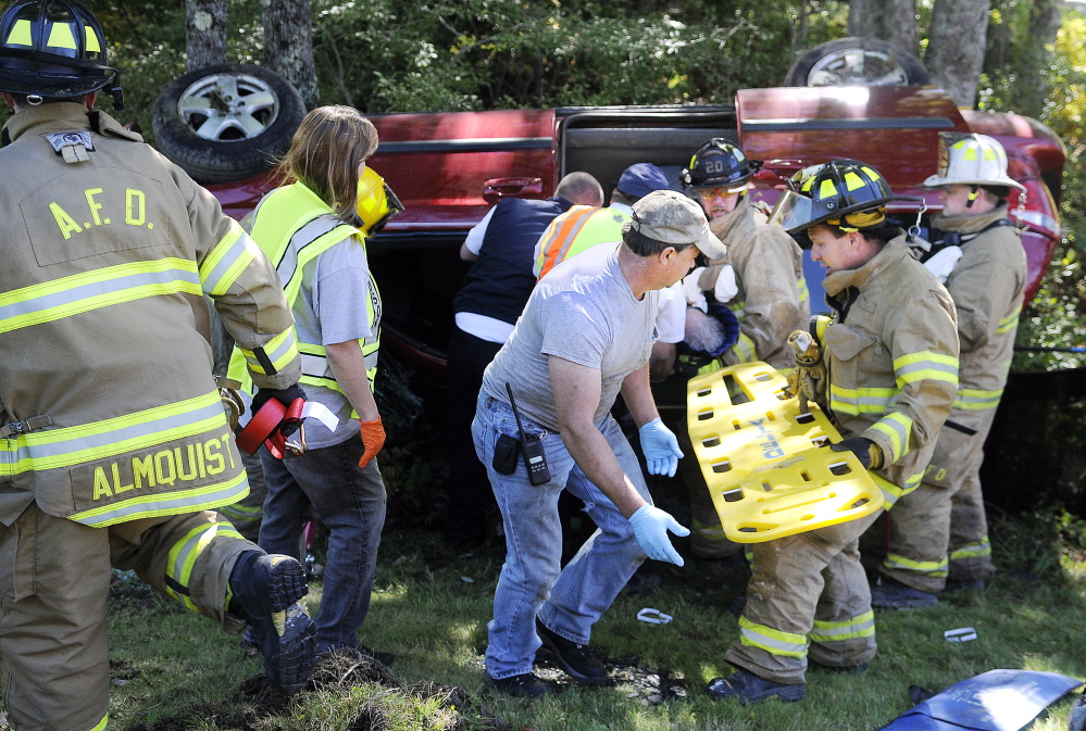 Windsor and Augusta firefighters prepare to extricate one of two women trapped in a van that rolled over Monday on Route 17 in Windsor. Police said Tuesday the driver is likely to face charges.