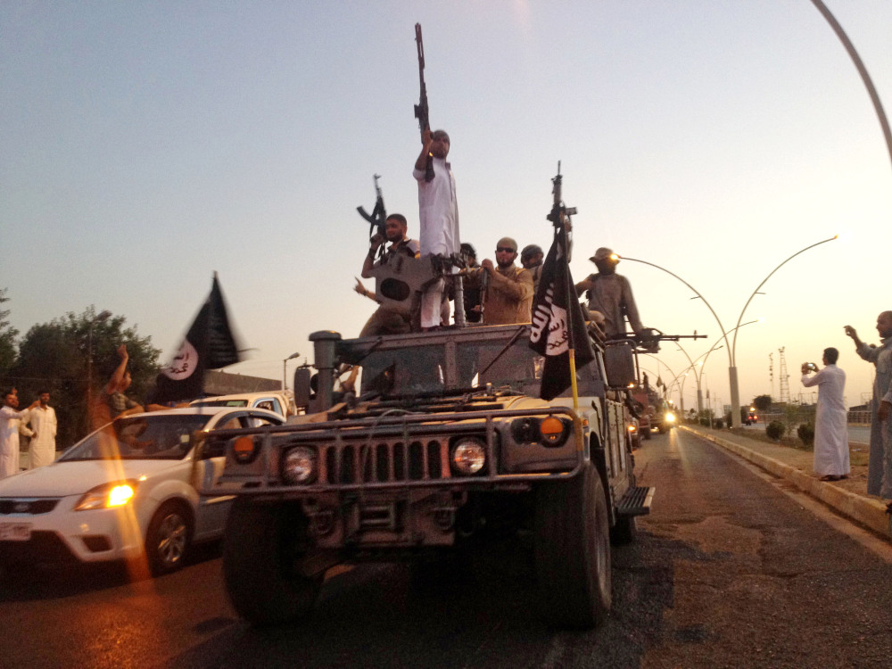 In this file photo taken Monday, June 23, 2014, fighters from the Islamic State group parade in a commandeered Iraqi security forces vehicle down a main road in the northern city of Mosul, Iraq.
