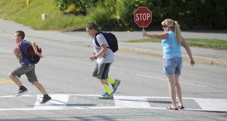 Former crossing guard Sherry McArthur escorts students on Aug. 28 across Western Avenue in Augusta. McArthur has volunteered to help students cross after the city eliminated crossing guards over the summer. Augusta residents can weigh in on the change Thursday with the Board of Education.