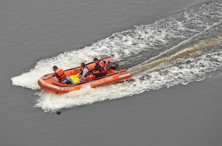 Waterville firefighters retrieve a woman in the Kennebec River who jumped from Carter Memorial Bridge on the Winslow and Waterville town line on Tuesday.