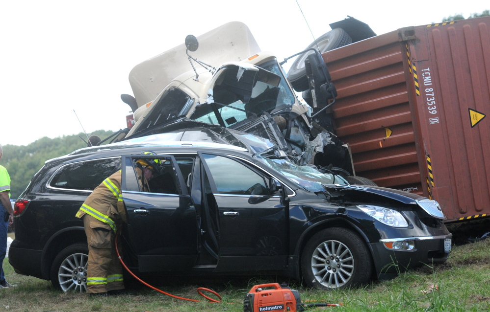 Maine State Police, Kittery fire and police respond to a two-vehicle accident involving an overturned tractor-trailer truck Thursday on the Maine Turnpike in Kittery. Police said a woman died when the truck crashed through a guardrail, crossed a median and hit her SUV head-on. AP Photo/Seacoastonline, Deb Cram