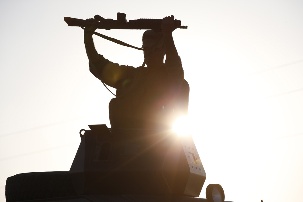 A Turkish soldier adjusts his rifle atop of an armoured vehicle as it moves to its new position at Mursitpinar near Suruc, at the Turkey-Syria border, Sunday as fighting intensified between Syrian Kurds and the militants of Islamic State group in Kobani.