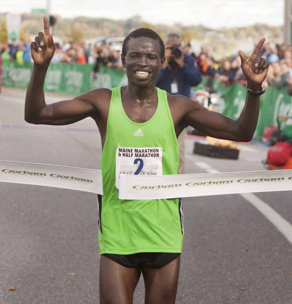 Moninda Marube of Auburn celebrates as he crosses the finish line winning the Maine Marathon in Portland on Sunday.