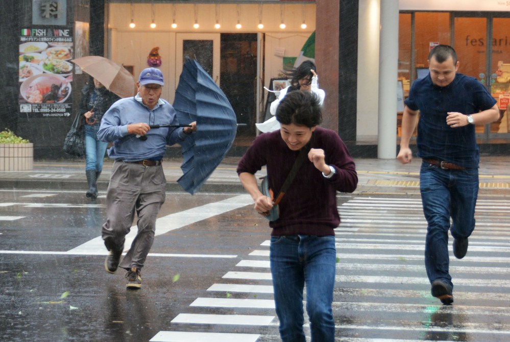 Pedestrians struggle to cross a street in Miyazaki, southern Japan, in heavy rain and strong winds caused by a powerful typhoon approaching to Japan Sunday.