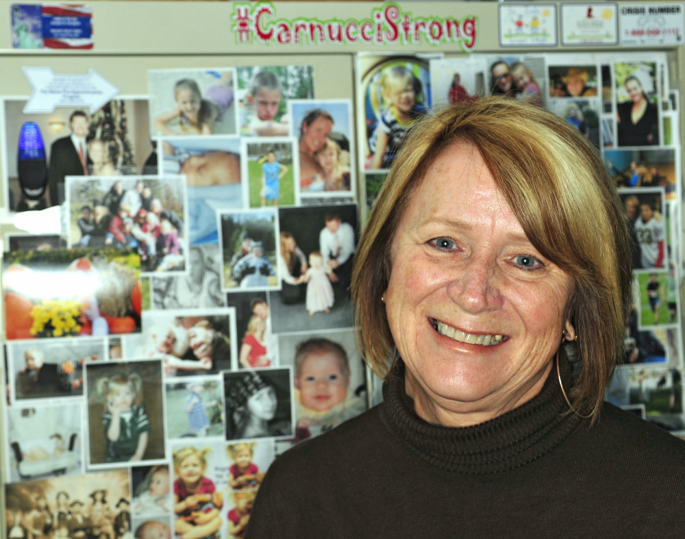 Charle Clark displays aCarnucci Strong sign and a display of family photos in her office on Thursday at the Winthrop police station. Her daughter, Jaime Carnucci, is recovering from a spinal injury.