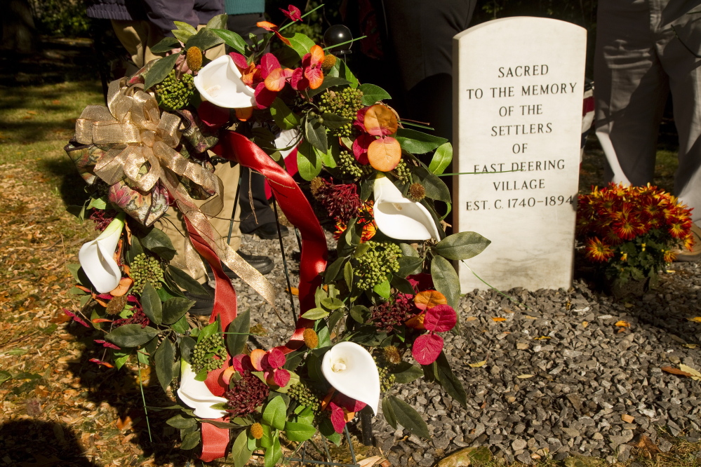 A wreath sits next to a memorial stone for the early settlers of East Deering.