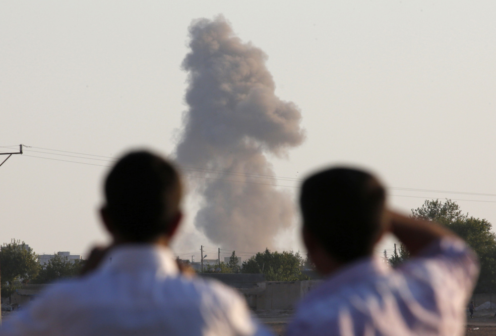 Turkish Kurds on the outskirts of Suruc, on the Turkey-Syria border, watch smoke rise after an airstrike in Kobani, Syria, where the fighting between the Islamic State group and Kurdish forces intensified Tuesday.
