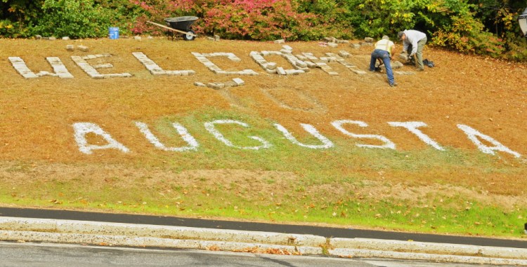 City workers Andy Chavarie, left, and Robert O’Connor set a granite cobblestones in place Tuesday for the giant letter E in the “Welcome to Augusta” message that’s on Rines Hill, south of downtown Augusta. The cobblestones were salvaged during the recent renovation of Market Square.