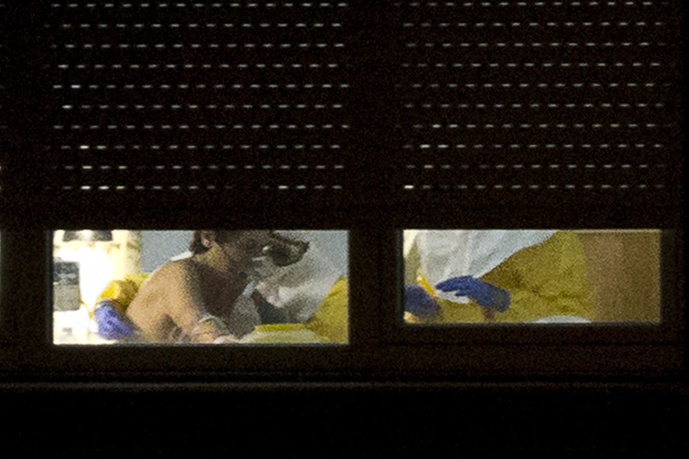 A medical practitioner wearing protective clothing stands next to an isolated patient on the sixth floor of the the Carlos III hospital in Madrid, Spain, Saturday.