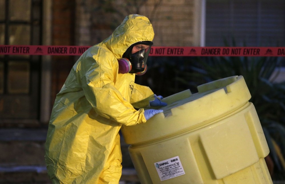 A hazmat worker moves a barrel while finishing up cleaning outside an apartment building of a hospital worker, Sunday, Oct. 12, 2014, in Dallas. The Texas health care worker, who was in full protective gear when they provided hospital care for Ebola patient Thomas Eric Duncan, who later died, has tested positive for the virus and is in stable condition, health officials said Sunday. (AP Photo/LM Otero)