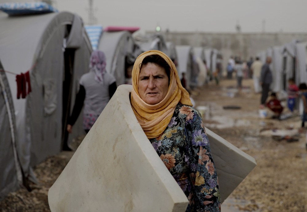 A Syrian Kurdish refugee who fled Kobani, carries a mattress to the family tent at a refugee camp in Suruc, Turkey, on the Turkey-Syria border. The predominantly Kurdish town of Kobani has been transformed from a dusty backwater into a symbol of resistance for Kurds around the world.