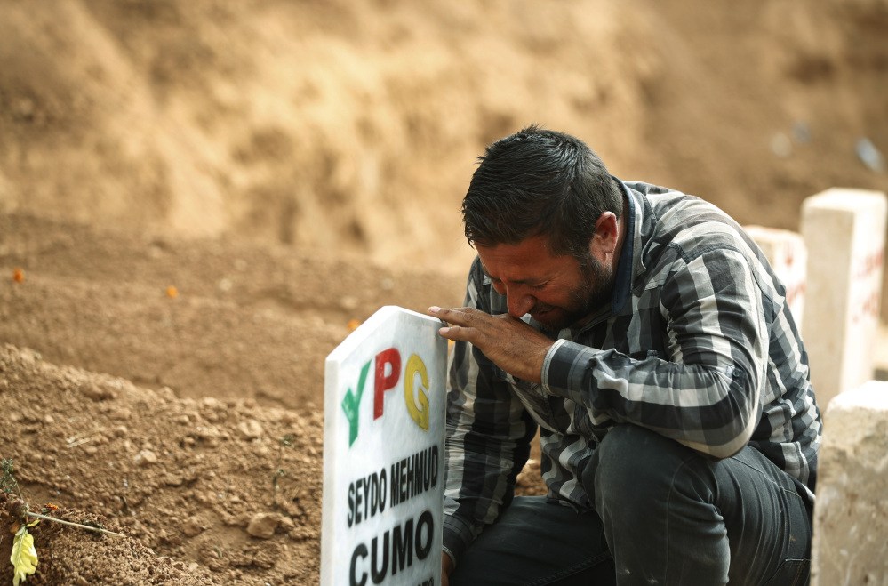 In this Saturday, file photo, Kurdish Ali Mehmud mourns at the grave of his brother Seydo Mehmud ‘Curo’, a Kurdish fighter, who was killed in the fighting with the militants of the Islamic State group in Kobani, Syria, and was buried at a cemetery in Suruc, Turkey.