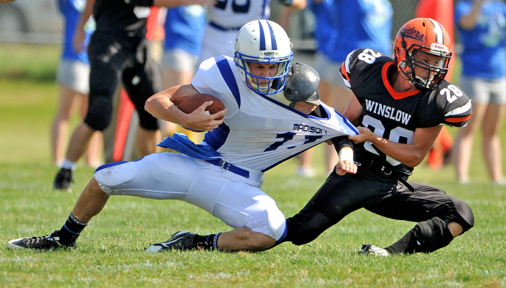 Winslow’s Luke Fredette, right, brings down Madison/Carrabec quarterback Chase Malloy during a game Sept. 6 in Winslow.