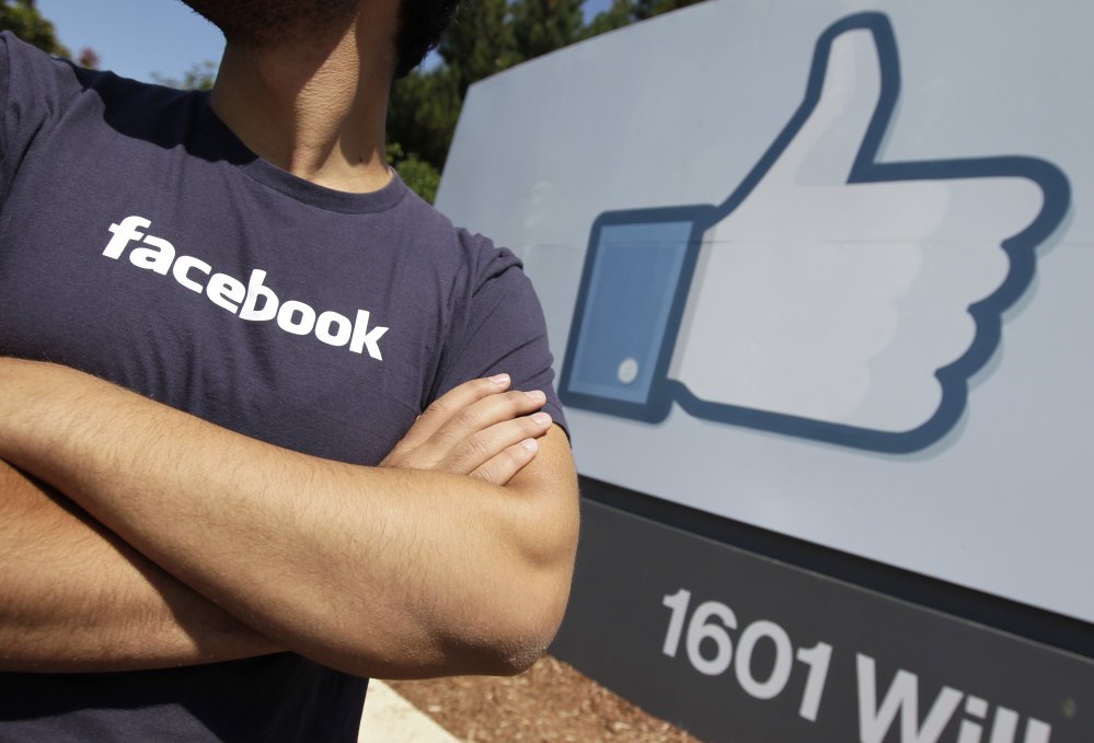In this Aug. 17, 2012 file photo, a Facebook worker waits for friends to arrive outside of Facebook headquarters in Menlo Park, Calif.