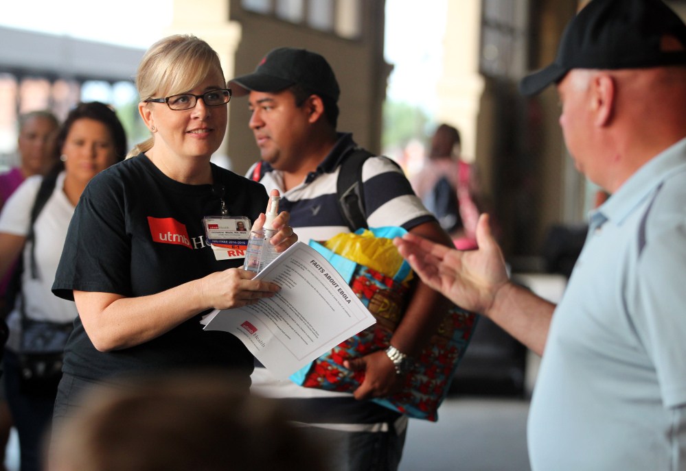 Christine Wade, a registered nurse at the University of Texas Medical Branch, greets Carnival Magic passengers disembarking in Galveston, Texas on Sunday. Nurses met passengers with Ebola virus fact sheets and to answer any questions.
