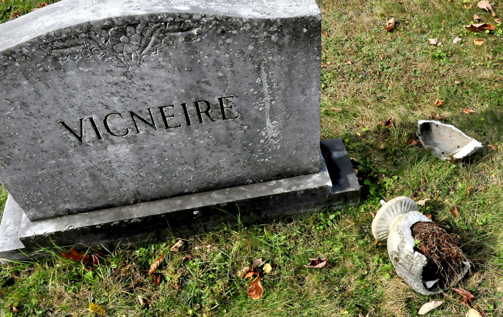 Pieces of a flower pot lie beside a grave marker Monday at the Maloon Cemetery in St. Albans, where vandals toppled gravestones last week.