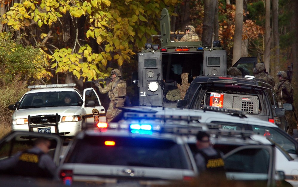 U.S. Marshals Service members aim their rifles toward the woods on Lower Swiftwater Road on Saturday, in Swiftwater, Pa., during a massive manhunt for killer Eric Frein.