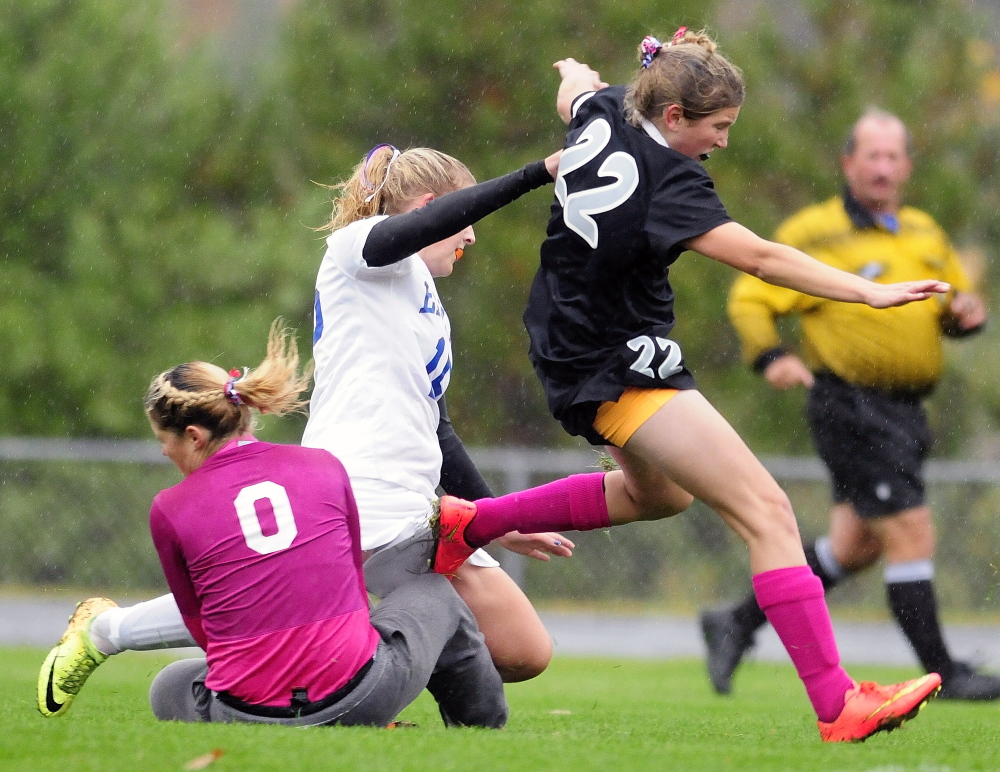 Lincoln Academy keeper Miranda Achorn, left, makes a save as Erskine midfielder Mallory Chamberlain, center, and Lincoln’s Brie Wajer collide with her  during a game Tuesday in South China.