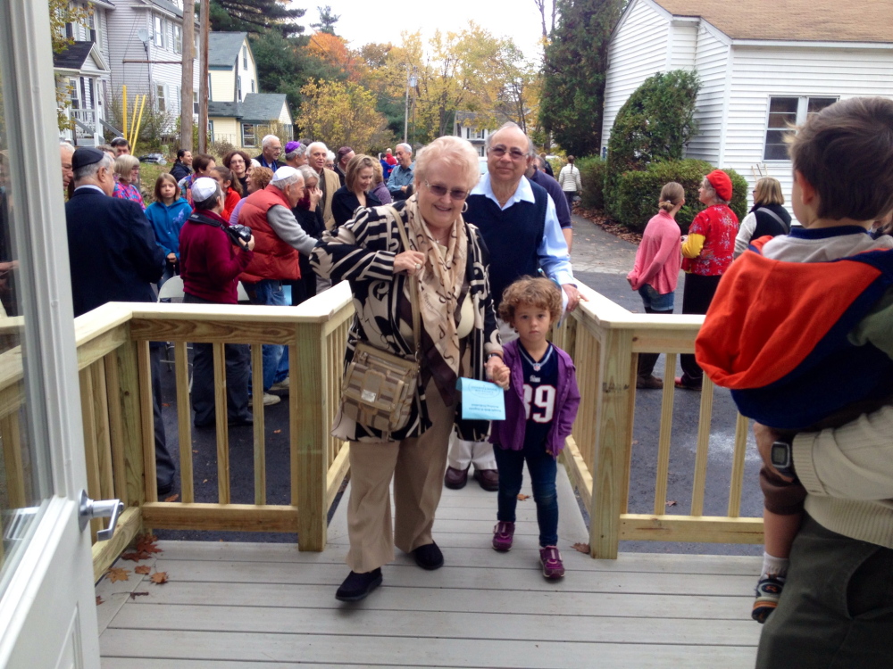 Nancy and Charles Shuman of Winthrop walk with their four-year-old granddaughter, Sophie Shuman, into the new building on Woodlawn Street in Augusta that bears their names and will house the synagogue’s religious school and office space.